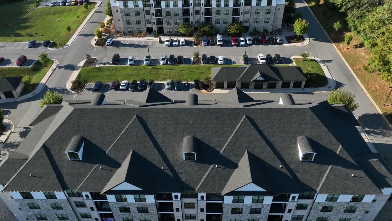 Drone backwards shot of parking cars in front of luxury multi family unit house in USA. Sunny day in autumn season. Upper class residential area in suburbia