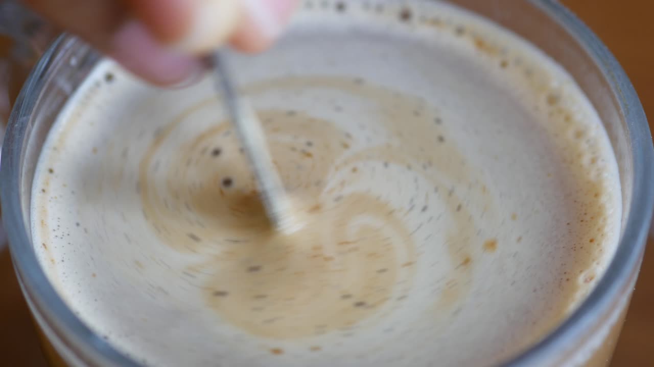 Close up of a coffee cup being stirred with a spoon
