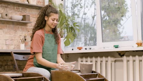 angestellte, die in einer werkstatt ein keramikstück auf einer töpferscheibe modelliert 3