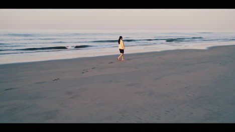 woman walking on the beach at sunrise/sunset