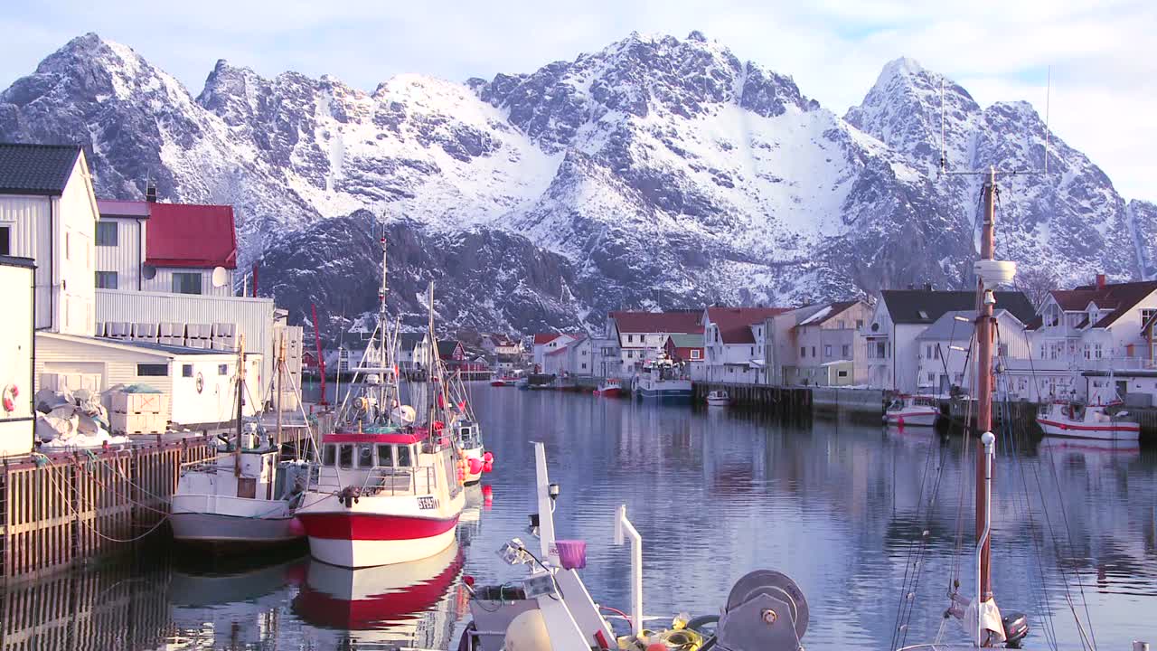 montañas cubiertas de nieve se reflejan en un puerto en un pequeño pueblo de pescadores en las islas árticas de lofoten noruega 4