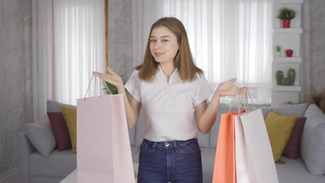 una joven muestra sus bolsas de compras a la cámara y está positivamente feliz.