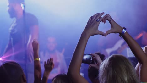 Animation-of-caucasian-woman-gesturing-heart-on-concert