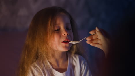 girl eats grudgingly porridge with mother in bedroom