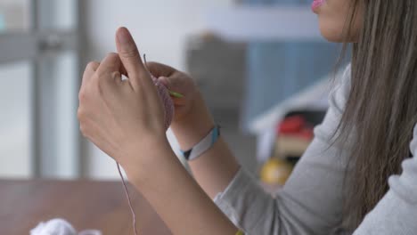 closeup view of woman holding thin crochet needles as she works on them