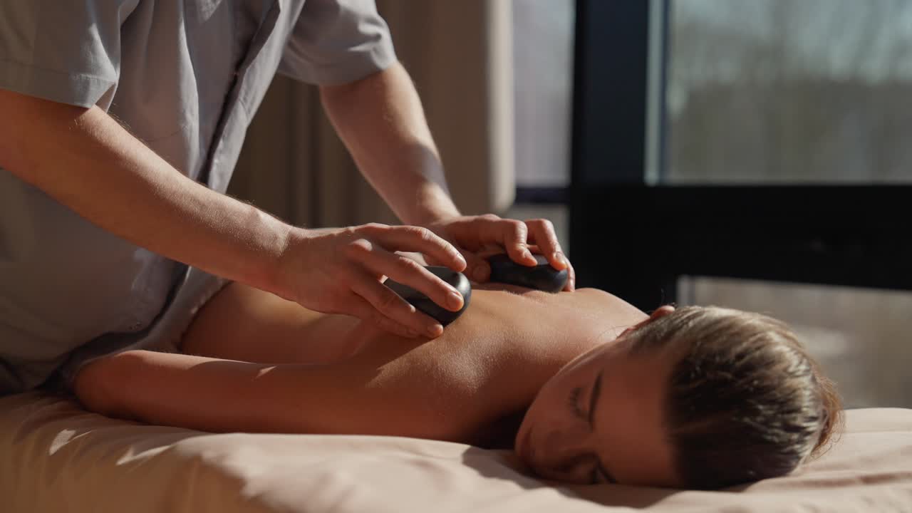 Kvinde modtager hot stone massagebehandling på et spa