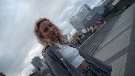 Smiling-woman-standing-downtown-in-modern-city-buildings-area.