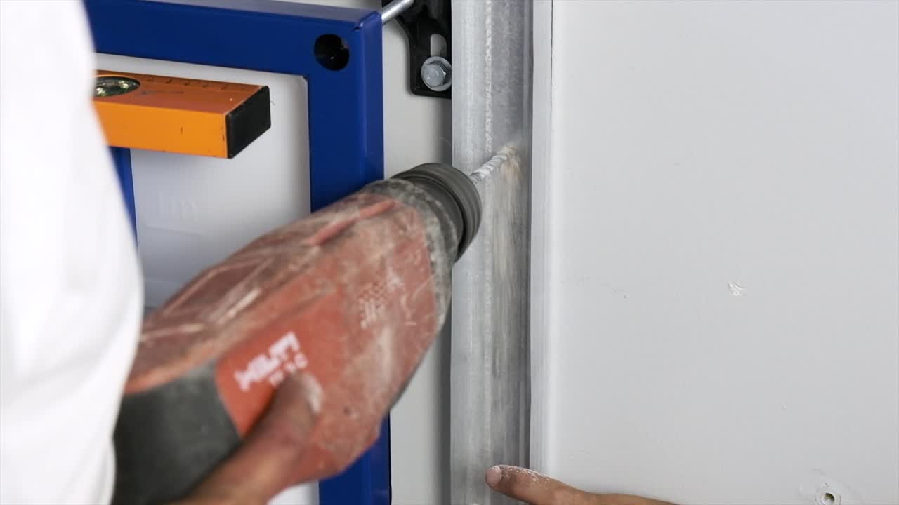 el maestro hace un agujero en la pared con un taladro eléctrico