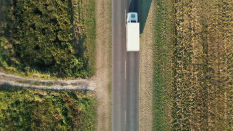 Aerial-drone-view-of-a-refrigerated-transport-truck-traveling-on-a-straight-road