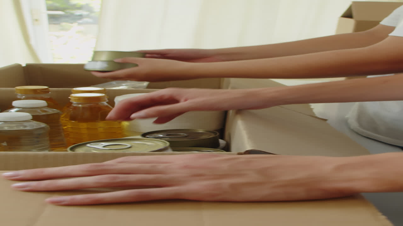 Hands of Donation Center Volunteers Giving Food to People
