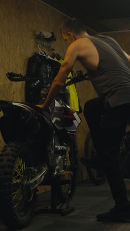 man fixing a dirt bike in a garage