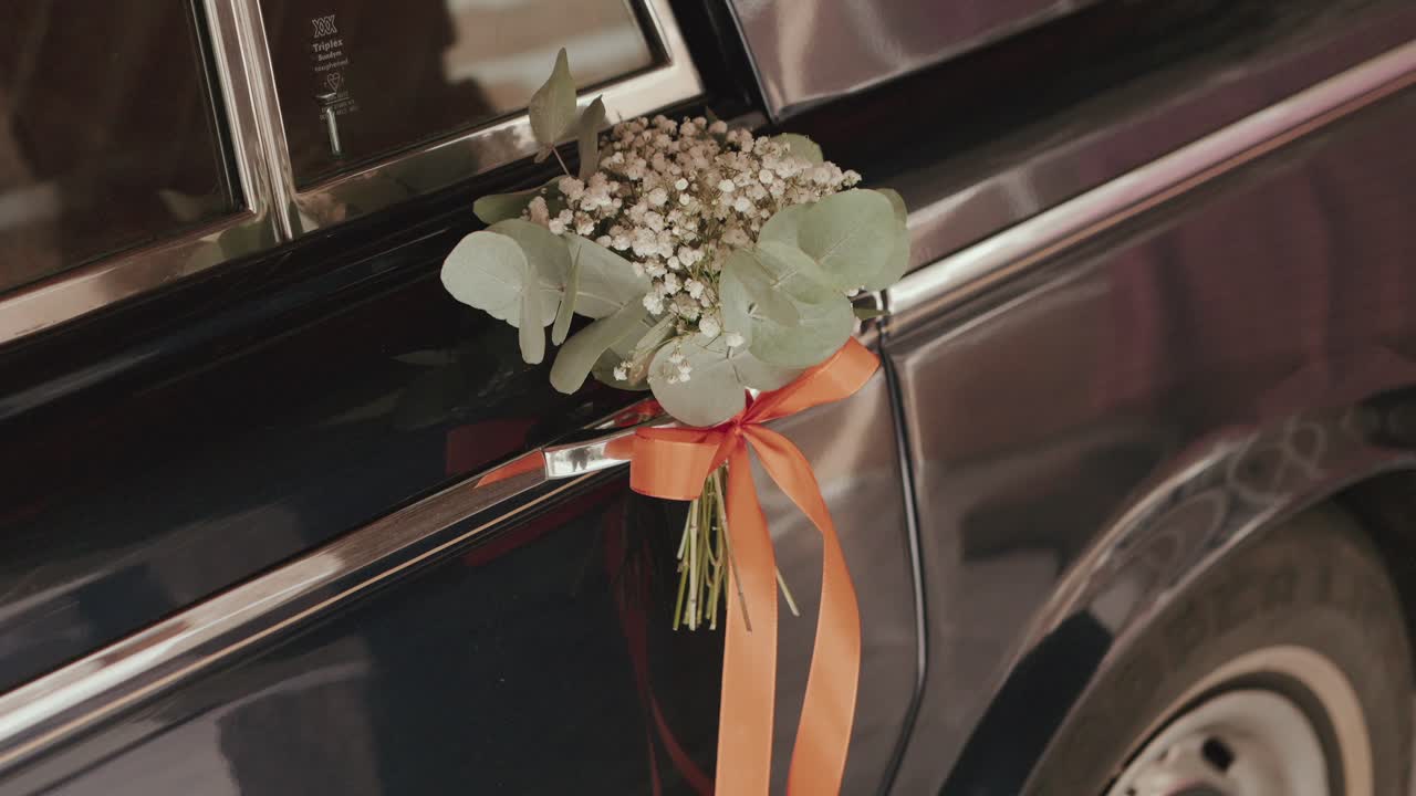 주황색 리본으로 묶여 차량 손잡이에 걸린 꽃다발