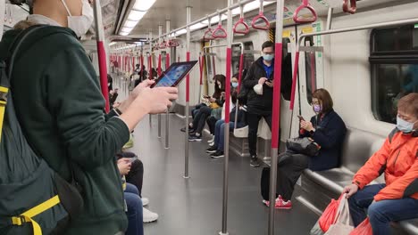 a handheld shot of people in hong kong wearing the mask during the coronavirus outbreak at the subway.