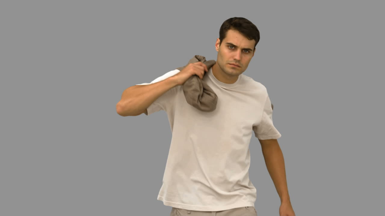 hombre guapo sosteniendo su abrigo en la pantalla gris