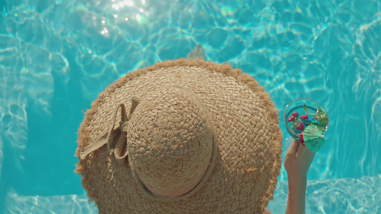 Woman in Straw Hat Enjoying a Cocktail by the Pool