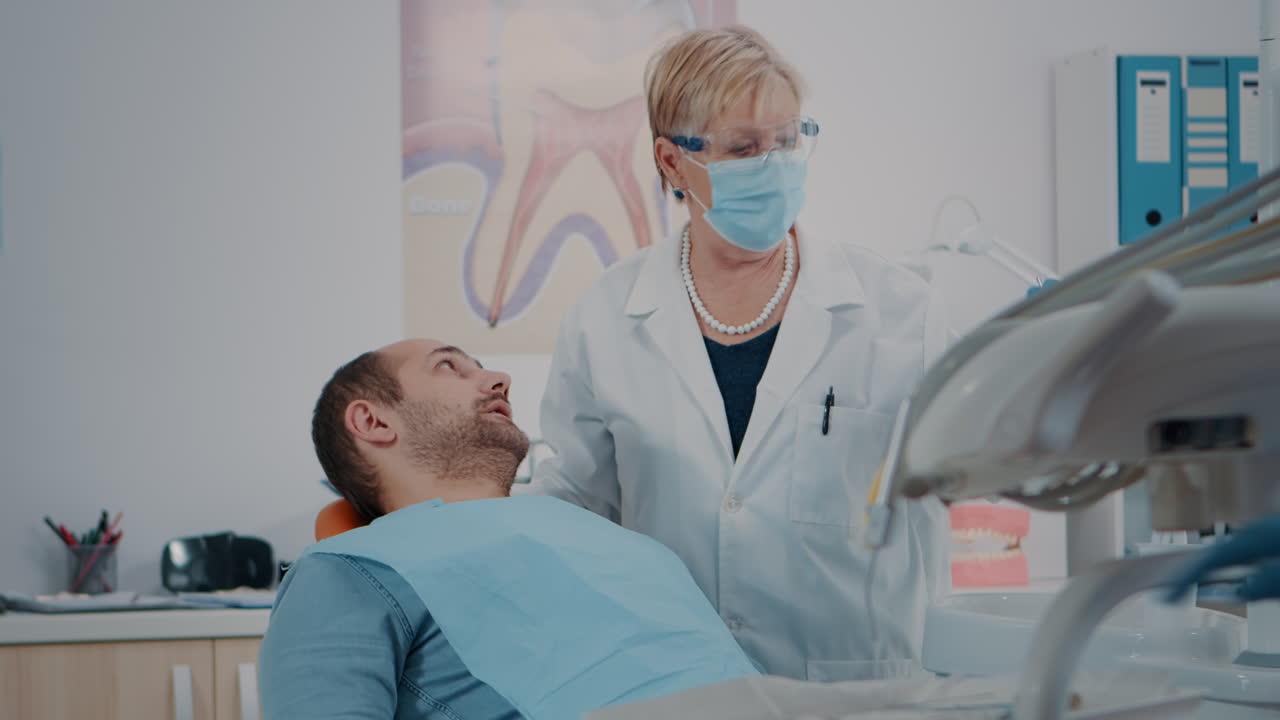 Paciente abriendo la boca y dentista examinando la dentadura.