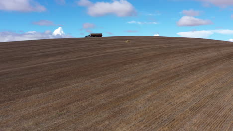 landscape with field and blue sky farmer working with giant trucks aerial shot