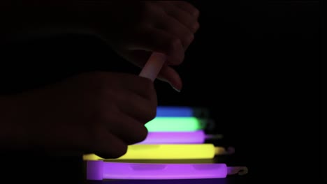 manos arreglando palos brillantes en la oscuridad