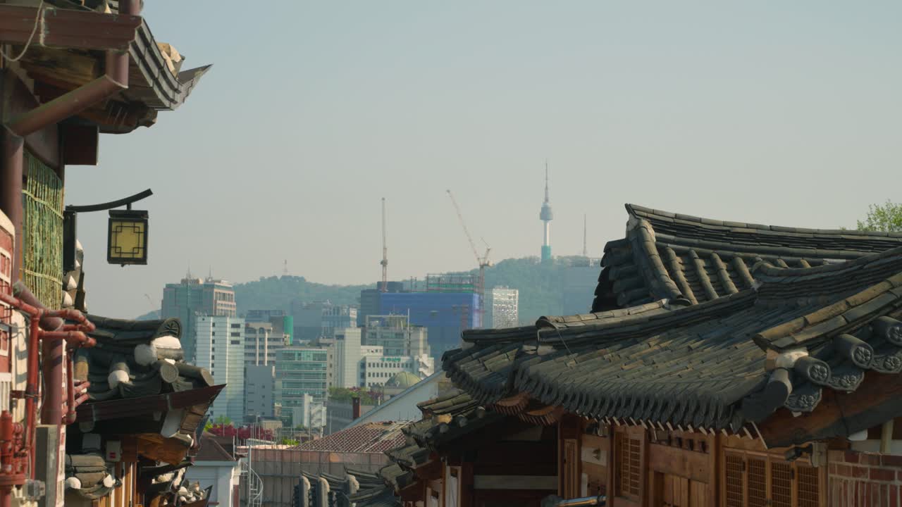 A charming alleyway in Bukchon Hanok Village, Seoul, showcases traditional Korean architecture and offers a picturesque view of the distant N Seoul Tower, High Angle Shot