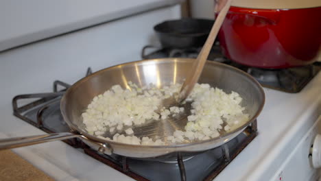 revolviendo cebollas salteadas chisporroteando en la estufa para una receta casera