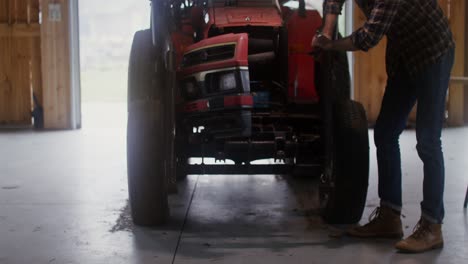 farmer repairing a tractor in a barn