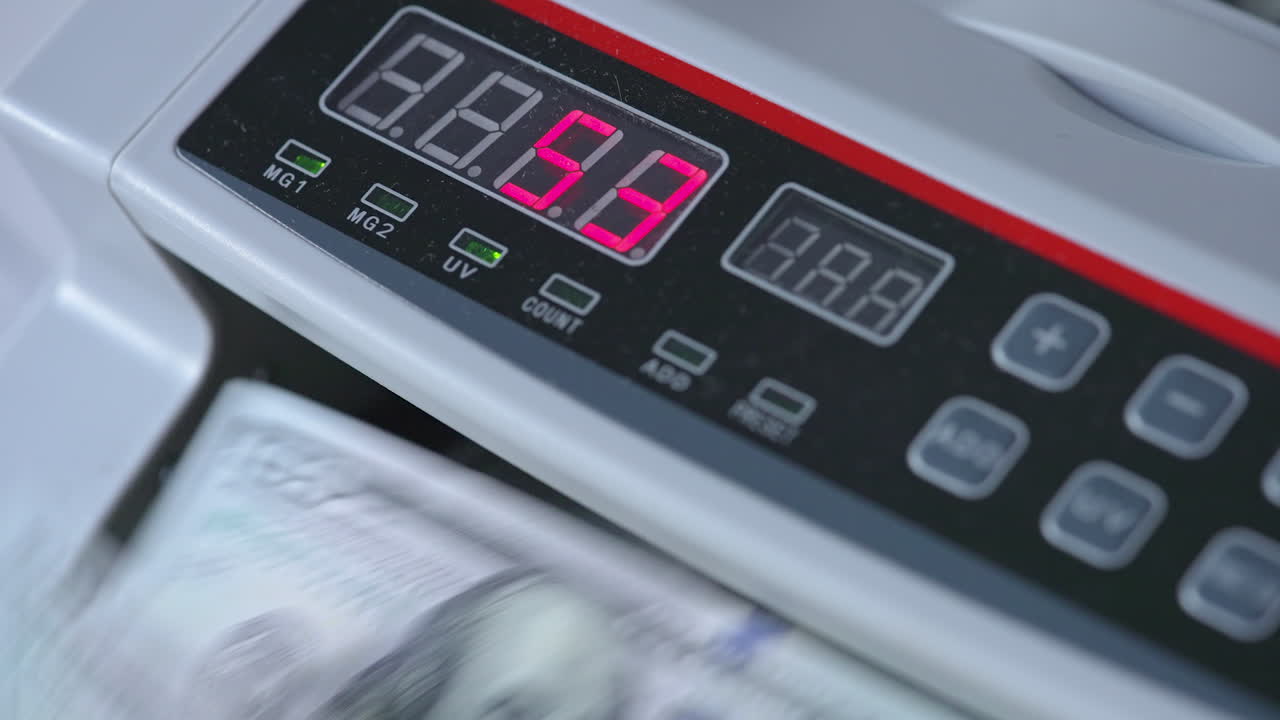 Electronic scoreboard of cash counting machine with numbers on. Dollar bills rotating in the device. Close up.