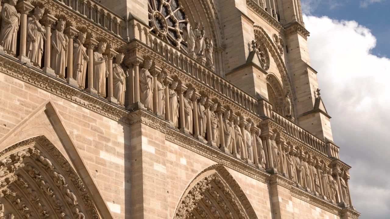 Inquadratura dal basso della facciata in pietra ornata e delle sculture di Notre Dame, Parigi