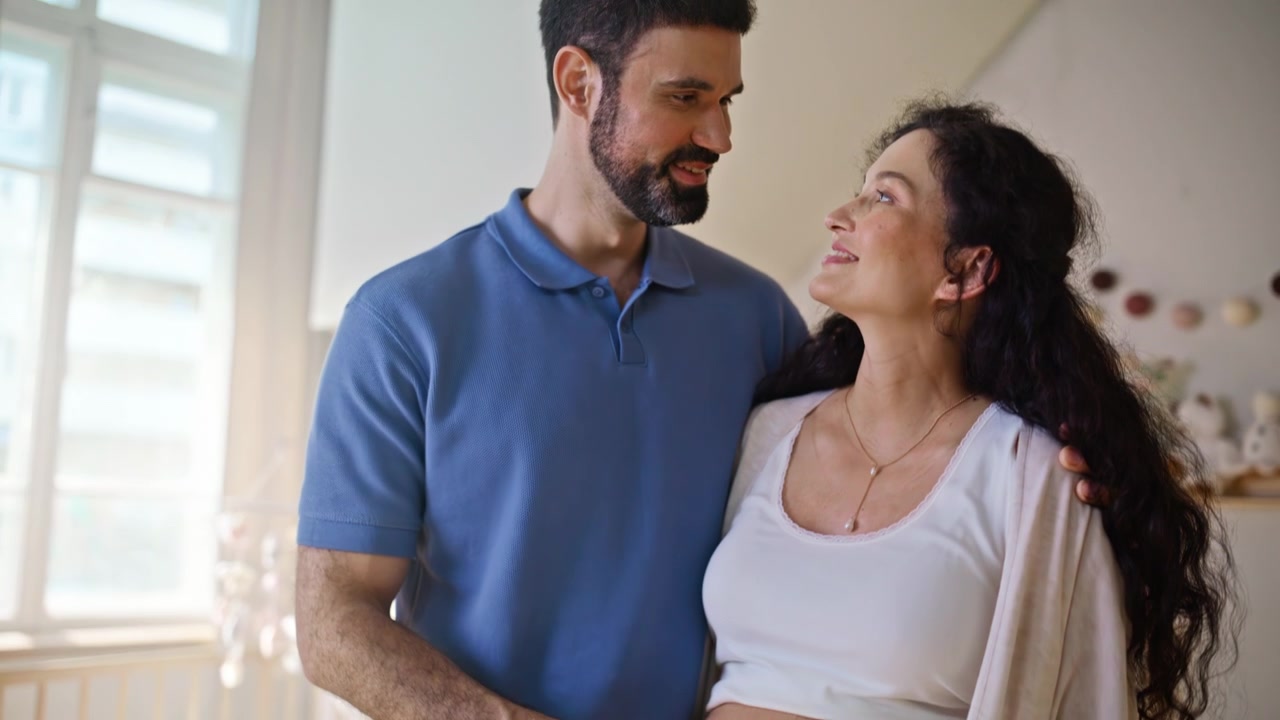 Casal à espera preparando fraldas de bebê para o quarto do bebê. Mulher grávida e marido em casa