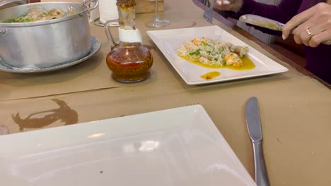 un individuo maneja hábilmente el tenedor y el cuchillo para mezclar y saborear su comida en un plato, celebrando el arte de la preparación culinaria y el placer de comer