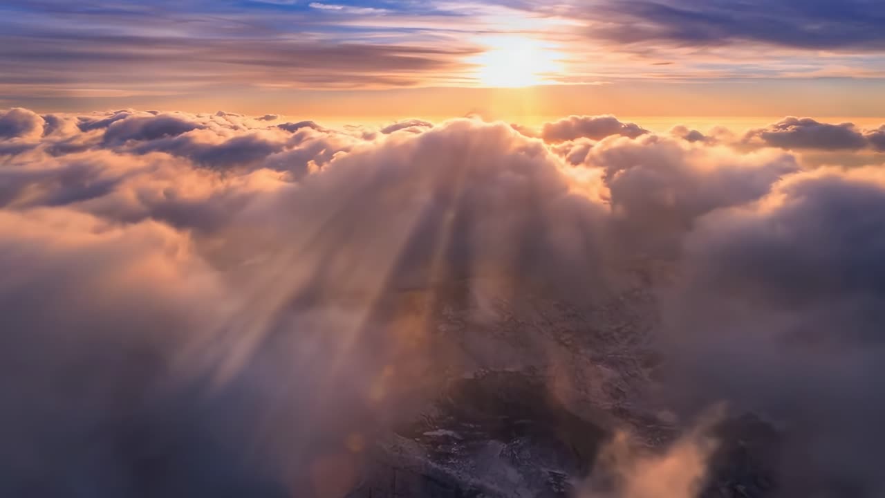 Video aereo che cattura un'alba mozzafiato sopra le nuvole, con raggi solari che filtrano