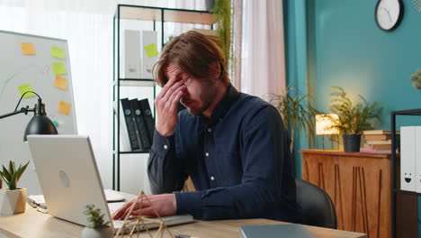 bored sleepy businessman worker working on laptop rubbing eye pinch nose, pain headache at office