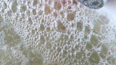primer plano de las burbujas en la bañera de agua caliente. a través de burbujas de jabón visibles piernas persona descansando. el concepto de descanso y recreación
