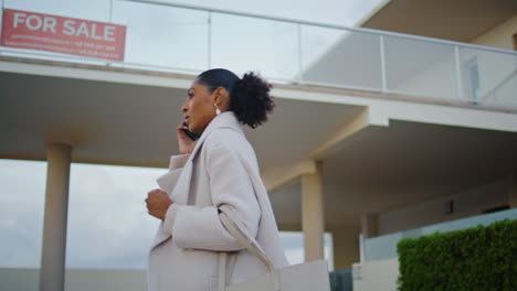 realtor woman speak smartphone on street. wealthy african american check house