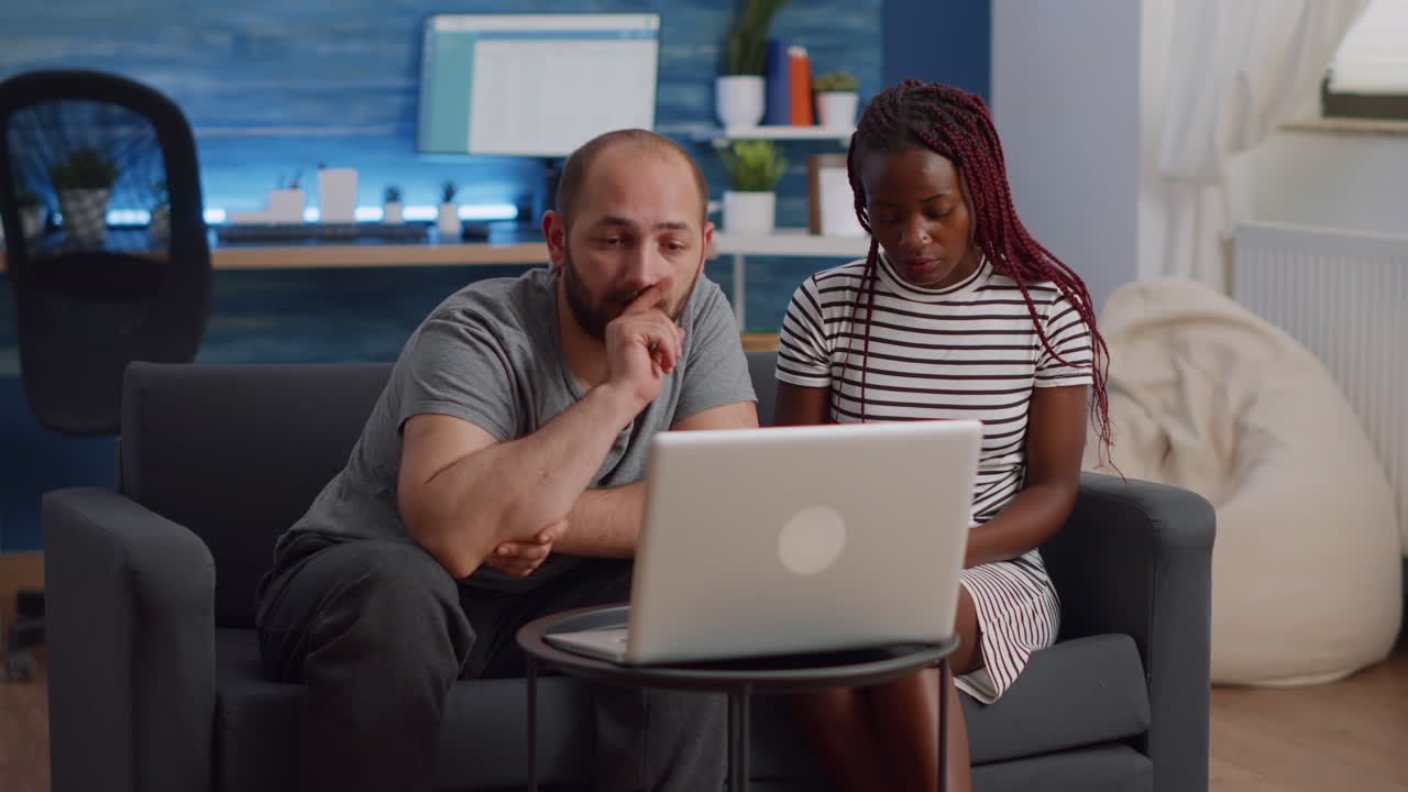 Modern interracial couple doing taxes with laptop and notebook