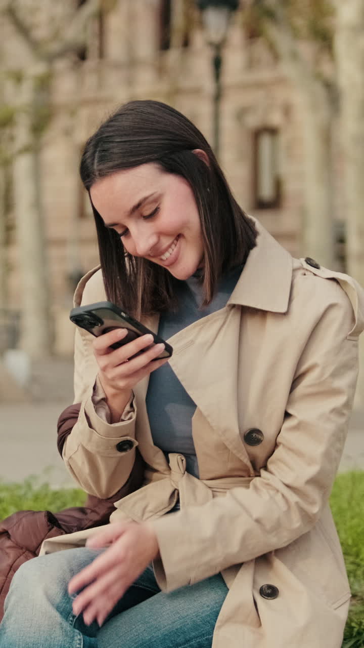 Giovane donna felice che sorride e usa lo smartphone all'aperto.