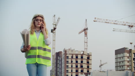 diálogo por teléfono una mujer con casco en el fondo de la construcción discute con el director del sitio de construcción del edificio.