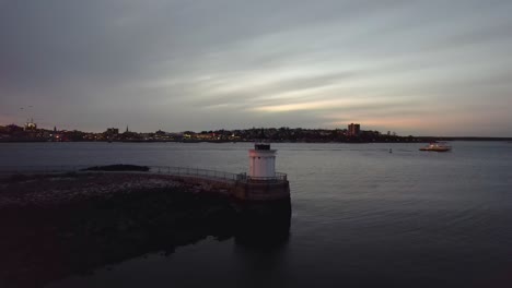 Faro-Del-Rompeolas-De-Portland,-Luz-De-Insectos-Al-Atardecer,-Alejamiento-Cinemático-Aéreo-En-Portland,-Maine