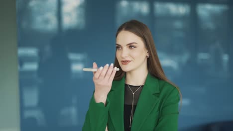 hermosa mujer con ropa profesional graba un mensaje de voz en su teléfono inteligente