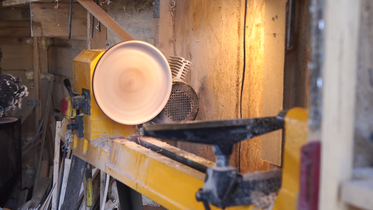 el carpintero pinta la placa de madera con el pincel.