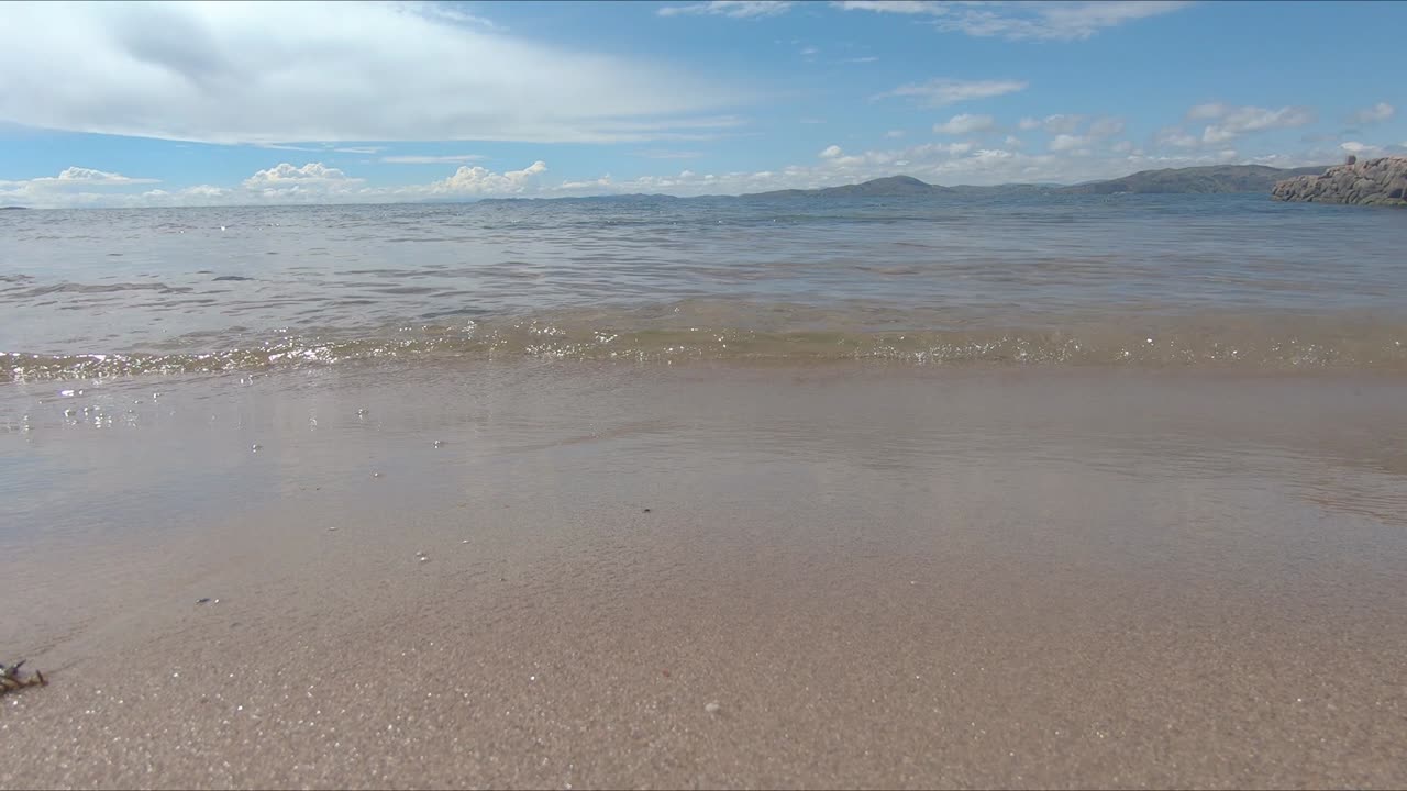 티티카카 호수 (titicaca lake) 의 아름다운 해변의 모래에 스프레이싱하는 작은 파도