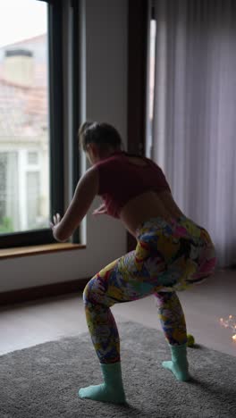 woman doing squats at home by the window