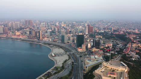 reveal traveling back, luanda city, golden hour flying over luanda bay, africa