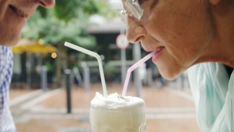 Senior-couple-sharing-a-mug-of-coffee-using-straws-4k