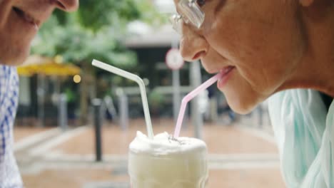 pareja de alto nivel compartiendo una taza de café usando pajitas 4k