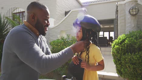 Glücklicher-Afroamerikanischer-Vater,-Der-Seiner-Tochter-Hilft,-Einen-Helm-Aufzusetzen