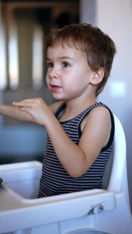 little toddler boy refuses to eat. mom gives porridge on the spoon to her son but he turns away. vertical video.