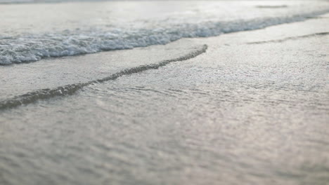 small beach waves ripples approaching the shore line in mangalore, india, evening handheld slow motion shot