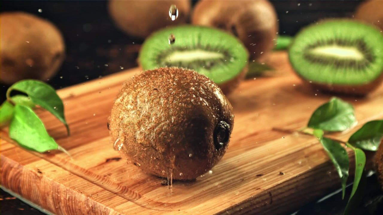 Gocce d'acqua che schizzano su kiwi fresco al rallentatore.