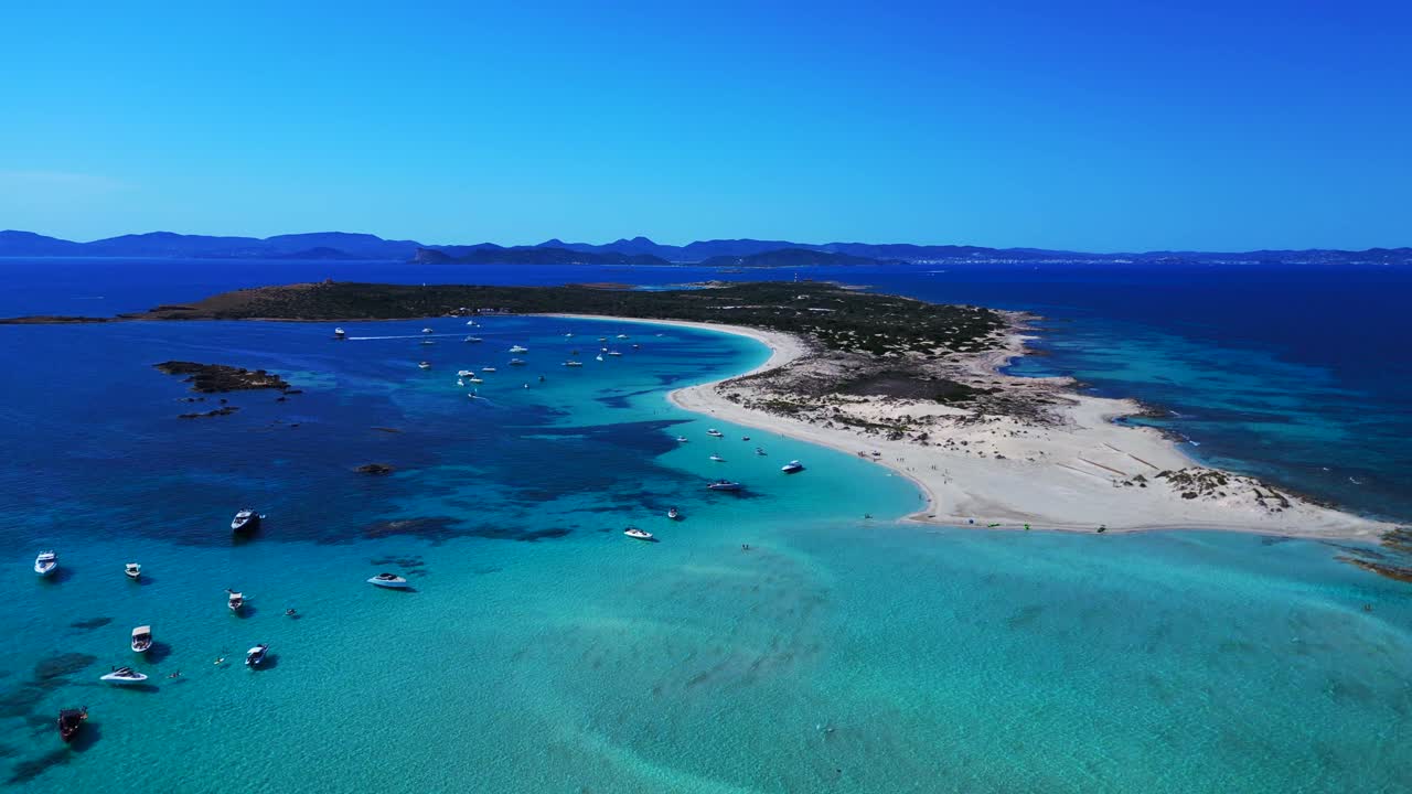 Isola di Espalmador con spiagge di sabbia bianca, acqua turchese cristallina e barche ancorate. Ibiza e l'isola di Es Vedrà sullo sfondo. Bella ripresa aerea dall'alto effettuata con un drone