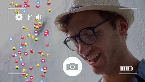 interfaz de la cámara sobre múltiples emoji de cara e iconos flotando contra el hombre caucásico sonriendo